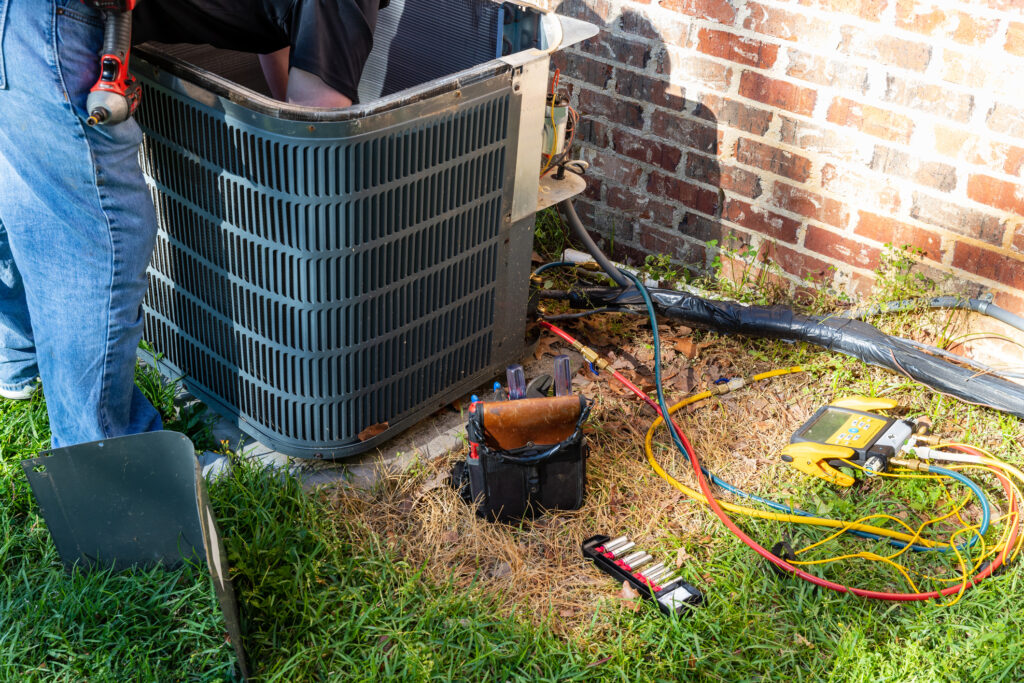 An outdoor air conditioner unit is being serviced by a technician.