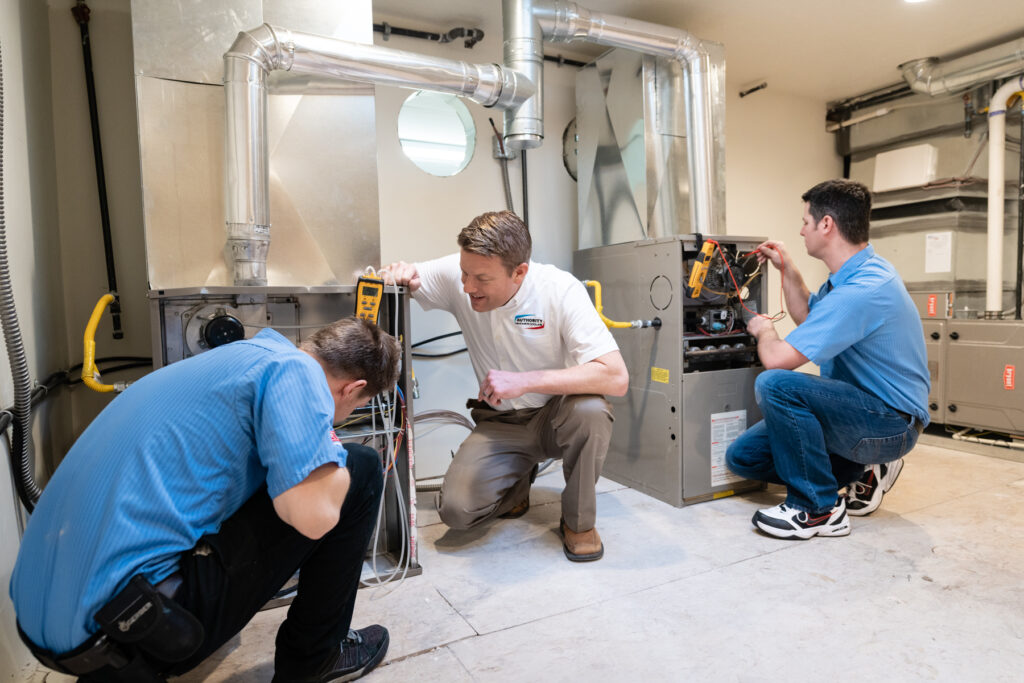 Three technicians work on HVAC units, indicating HVAC installation or repair services.
